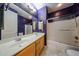 Bathroom featuring a double sink vanity, shower over tub, and purple accent wall at 16528 W Lariat Ln, Surprise, AZ 85387