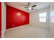 Bright bedroom featuring tile floors, a red accent wall, and a ceiling fan at 16528 W Lariat Ln, Surprise, AZ 85387