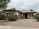 Charming single-story home with a brick driveway, manicured shrubs and stone accents around the windows at 16528 W Lariat Ln, Surprise, AZ 85387