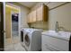 Tiled laundry room with modern washer and dryer, utility sink, and overhead cabinets at 16528 W Lariat Ln, Surprise, AZ 85387