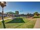 View of the community tennis courts with shade structures, surrounded by well-maintained lawns and fencing at 17830 N 45Th Ave, Glendale, AZ 85308