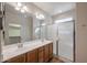 Bright bathroom features double sinks, wood cabinets, a large mirror, and a glass-enclosed shower at 18137 W Deer Creek Rd, Goodyear, AZ 85338