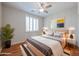 Inviting bedroom features wood floors, a ceiling fan, and bright lighting from side table lamps at 18137 W Deer Creek Rd, Goodyear, AZ 85338