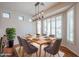 Elegant dining room bathed in natural light, featuring a modern chandelier and a beautifully set table for gatherings at 18137 W Deer Creek Rd, Goodyear, AZ 85338