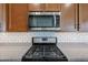 Close up of a stainless steel microwave and gas stove over a granite countertop with white subway tile backsplash at 18137 W Deer Creek Rd, Goodyear, AZ 85338