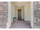 Covered entryway with a dark wood front door, a paver walkway, and stone pillars on either side at 18362 W Illini St, Goodyear, AZ 85338