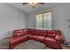 Cozy living room featuring a red leather sectional sofa, a window and ceiling fan at 18362 W Illini St, Goodyear, AZ 85338