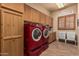 Well-lit laundry room featuring red washer and dryer, cabinets, countertops, tiled floors, and laundry themed decor at 20826 S Hadrian Way, Queen Creek, AZ 85142