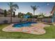 Sparkling pool with baja shelf, lush turf, travertine tile, and string lights create an entertainer's backyard at 3190 S Holguin Way, Chandler, AZ 85248