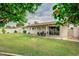 Expansive backyard features a covered patio and green lawn, framed by mature trees and perfect for outdoor living at 327 E La Jolla Dr, Tempe, AZ 85282