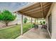 Covered patio with room for seating overlooks a spacious backyard with green grass and shade trees at 327 E La Jolla Dr, Tempe, AZ 85282