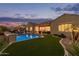 Stunning backyard view of a luxurious pool and well-maintained turf and landscaping at dusk at 3400 S Whetstone Pl, Chandler, AZ 85286