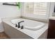 Freestanding white soaking tub with modern fixtures and plenty of natural light through window shutters at 3400 S Whetstone Pl, Chandler, AZ 85286