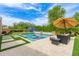 Beautiful backyard featuring a sparkling pool, charming patio furniture, and well-manicured artificial grass at 3400 S Whetstone Pl, Chandler, AZ 85286