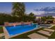 Backyard swimming pool with lush landscaping, outdoor seating, and privacy hedges at dusk at 3400 S Whetstone Pl, Chandler, AZ 85286