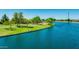 Scenic waterfront view with well-manicured lawn, mature trees, and tranquil blue water at 3400 S Whetstone Pl, Chandler, AZ 85286