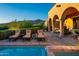 Relax in this cozy desert oasis with outdoor lounge chairs, mountain views, arched porch, and lush hedges at 40039 N 107Th Pl, Scottsdale, AZ 85262