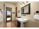 Elegant bathroom with pedestal sink, decorative mirror, and access to the outdoor area at 40039 N 107Th Pl, Scottsdale, AZ 85262