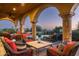 Relaxing covered patio offers comfortable seating, a stone-tiled floor, and views of the sparkling pool and green landscape at 40039 N 107Th Pl, Scottsdale, AZ 85262
