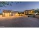 Expansive driveway with brick pavers leads to a spacious three-car garage at dusk at 40039 N 107Th Pl, Scottsdale, AZ 85262