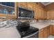This kitchen features tile backsplash, wooden cabinets, stainless steel microwave, and black electric stove at 4281 S Tecoma Trl, Gold Canyon, AZ 85118
