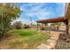 A lush backyard features grass, flower beds, and a covered patio by the fenced pool at 4510 W North Ln, Glendale, AZ 85302