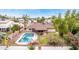Backyard featuring a refreshing pool, covered patio, and lush green space, surrounded by vibrant flowering bushes at 4510 W North Ln, Glendale, AZ 85302