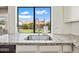 Close-up of a kitchen sink with granite countertops, white cabinets, and a view of the backyard at 5341 W Bloomfield Rd, Glendale, AZ 85304