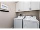 Well-organized laundry room featuring a side-by-side washer and dryer and white cabinets at 6550 S 24Th Pl, Phoenix, AZ 85042
