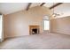 A spacious living room with a vaulted ceiling, cozy fireplace, and natural light from the windows at 7625 W Dreyfus Dr, Peoria, AZ 85381