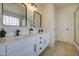 Modern bathroom with dual sinks, framed mirrors, black hardware, and glass enclosed tub-shower at 11629 W Washington St, Avondale, AZ 85323