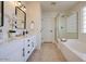 Bright bathroom with double sinks, a soaking tub, and a glass-enclosed shower at 11629 W Washington St, Avondale, AZ 85323