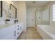 Bright bathroom with dual sinks, white cabinetry, black hardware, and glass enclosed tub-shower at 11629 W Washington St, Avondale, AZ 85323