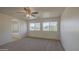 Bedroom with two windows, neutral carpet and an ensuite bathroom with a tub and shower at 11629 W Washington St, Avondale, AZ 85323