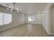 Bright, open living room with wood-look flooring, a modern chandelier, and ample natural light from large windows at 11629 W Washington St, Avondale, AZ 85323
