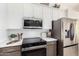 A chef's kitchen featuring stainless steel appliances, sleek countertops, and white and dark brown cabinets at 12529 N 83Rd Ln, Peoria, AZ 85381