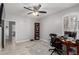 A home office features a ceiling fan, a wooden desk, a patterned rug, and built-in shelving at 13005 W Vista Paseo Dr, Litchfield Park, AZ 85340