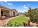 Well-manicured backyard featuring artificial turf, brick borders, desert landscaping, and covered patio with outdoor television at 1314 S Bridgegate Dr, Gilbert, AZ 85296