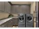 Convenient laundry room with gray cabinets, granite countertops, and stainless steel washer and dryer at 15536 E Heavenly Vista Trl, Fountain Hills, AZ 85268
