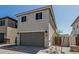 Charming two-story home with a gray garage door, desert landscaping, and a walkway gate at 15593 S 180Th Ln, Goodyear, AZ 85338