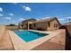 Resort-style backyard featuring a private pool with travertine tile surround, a covered patio and desert landscaping at 157 N 110Th Ave, Avondale, AZ 85323