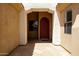 Arched doorway leading to a custom wood front door, complemented by stone tile flooring and exterior stucco walls at 157 N 110Th Ave, Avondale, AZ 85323