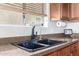 A well-lit kitchen sink with granite countertops, modern faucet, and a window with blinds at 157 N 110Th Ave, Avondale, AZ 85323