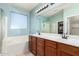 A primary bathroom with dual sinks, wood cabinetry, a large mirror, and a walk-in closet at 157 N 110Th Ave, Avondale, AZ 85323