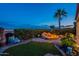 Backyard oasis with a rock fire pit, mature landscaping, and outdoor seating at twilight at 1617 E Copper Holw, Queen Creek, AZ 85140