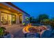 Scenic backyard at dusk with a stone patio, inviting fire pit, and covered outdoor dining at 1617 E Copper Holw, Queen Creek, AZ 85140