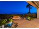 Inviting backyard with a captivating rock fire pit, lush greenery, and flagstone patio, creating a serene outdoor space at 1617 E Copper Holw, Queen Creek, AZ 85140