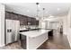 This kitchen showcases stainless steel appliances, dark cabinets, an island, and sleek white countertops at 19847 W Monroe St, Buckeye, AZ 85326