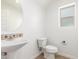 Clean, white half bathroom with pedestal sink, toilet, and window at 2046 E Paradise Ln, Phoenix, AZ 85022