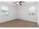 This bedroom features carpet, a ceiling fan, and natural light from two large windows at 2046 E Paradise Ln, Phoenix, AZ 85022